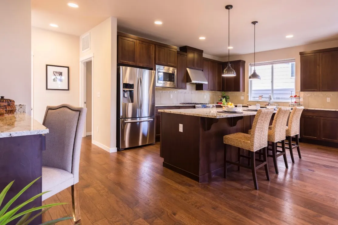 Modern kitchen with dark wood cabinets, granite countertops, stainless steel appliances, and a central island with bar seating.