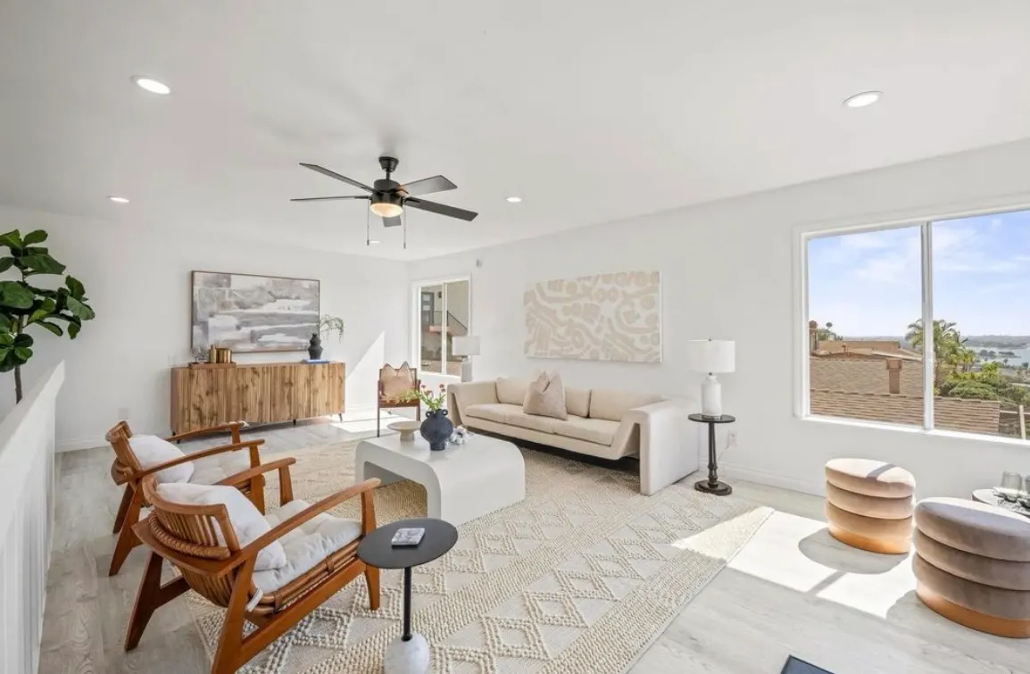 Bright, modern living room with light wood floors, white walls, minimalist decor, and large windows with a view.