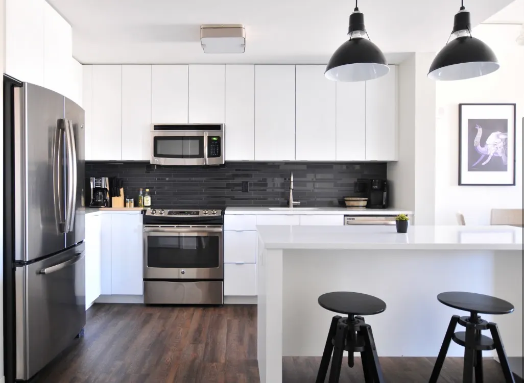 Modern kitchen with white flat-panel cabinets, dark subway tile backsplash, and stainless steel appliances.