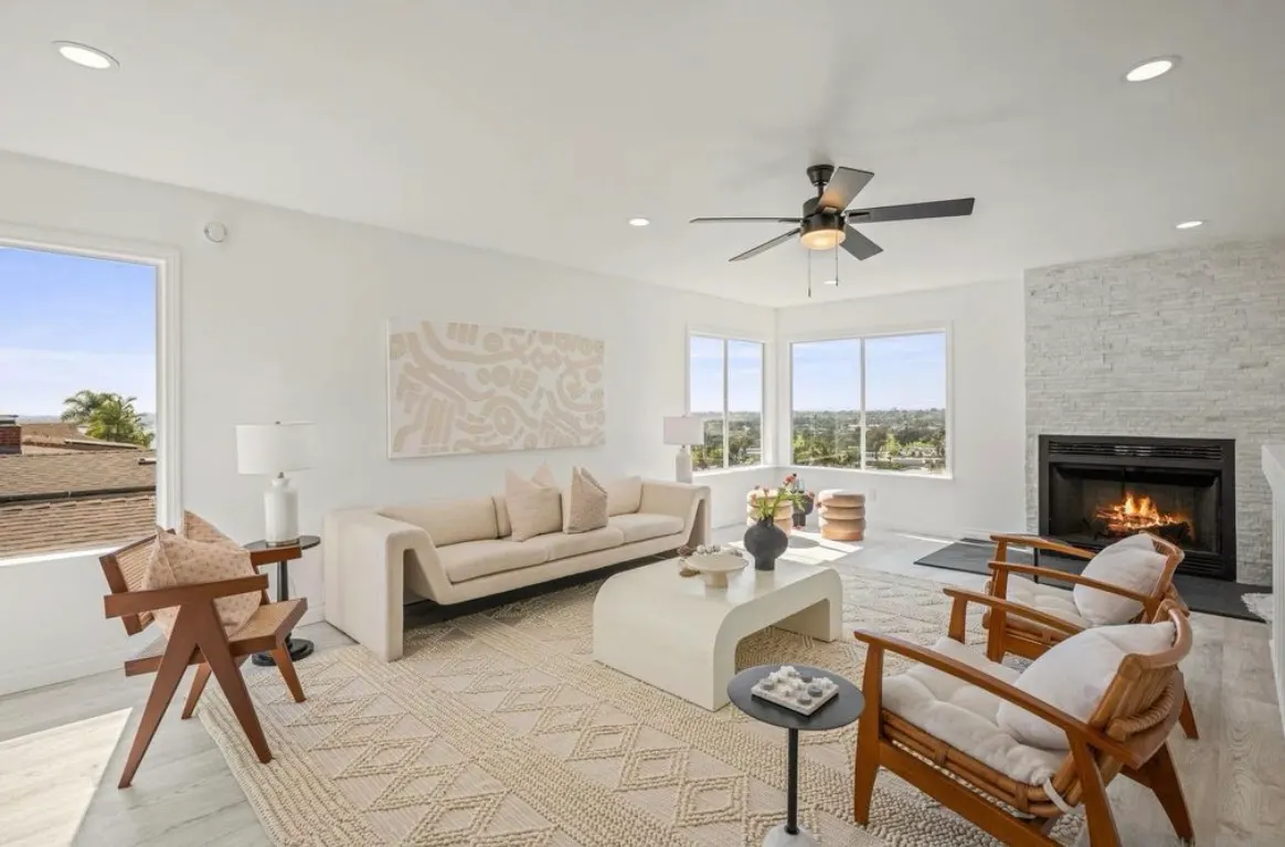 Bright living room with white walls, cozy fireplace, panoramic windows, and neutral modern decor.