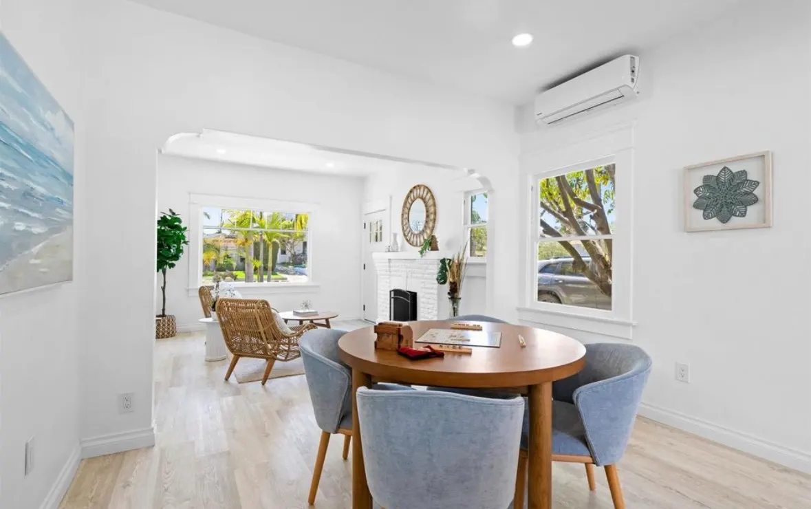 Bright living room remodel with light wood floors, white walls, rattan armchairs, and a modern dining set.