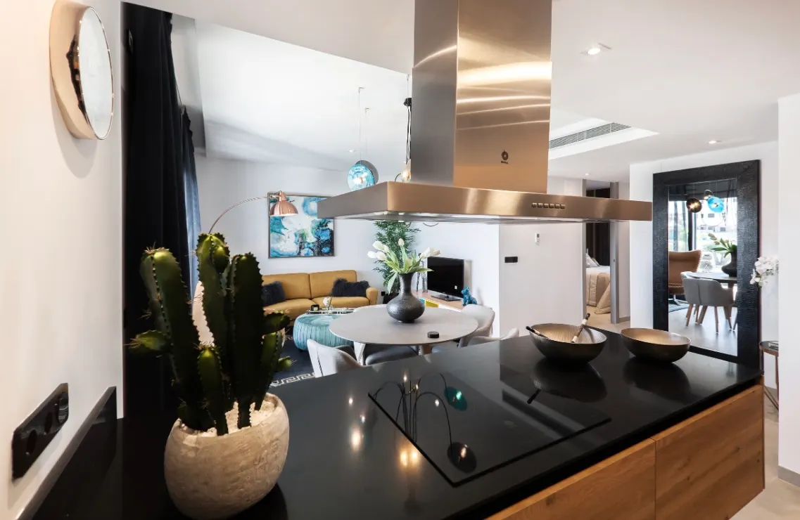 Modern open-concept living space with sleek black kitchen island, stainless steel range hood, and stylish dining area.