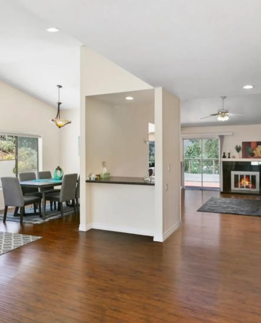 Open concept living space with hardwood floors, dining area, peninsula, and fireplace.