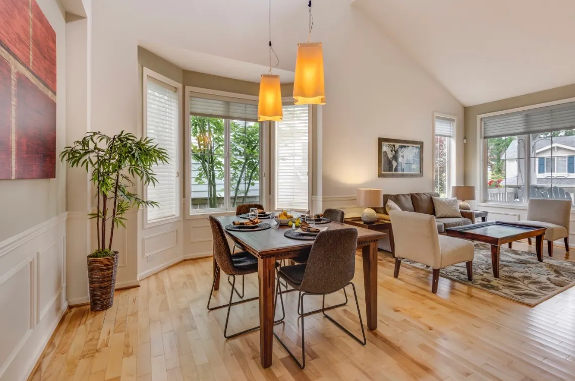 Modern open-concept dining and living room with vaulted ceilings, light wood floors, and neutral tones.