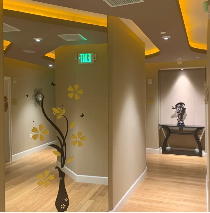 Warm-toned hallway featuring natural hardwood floors, decorative wall decals, recessed lighting, and a console table.