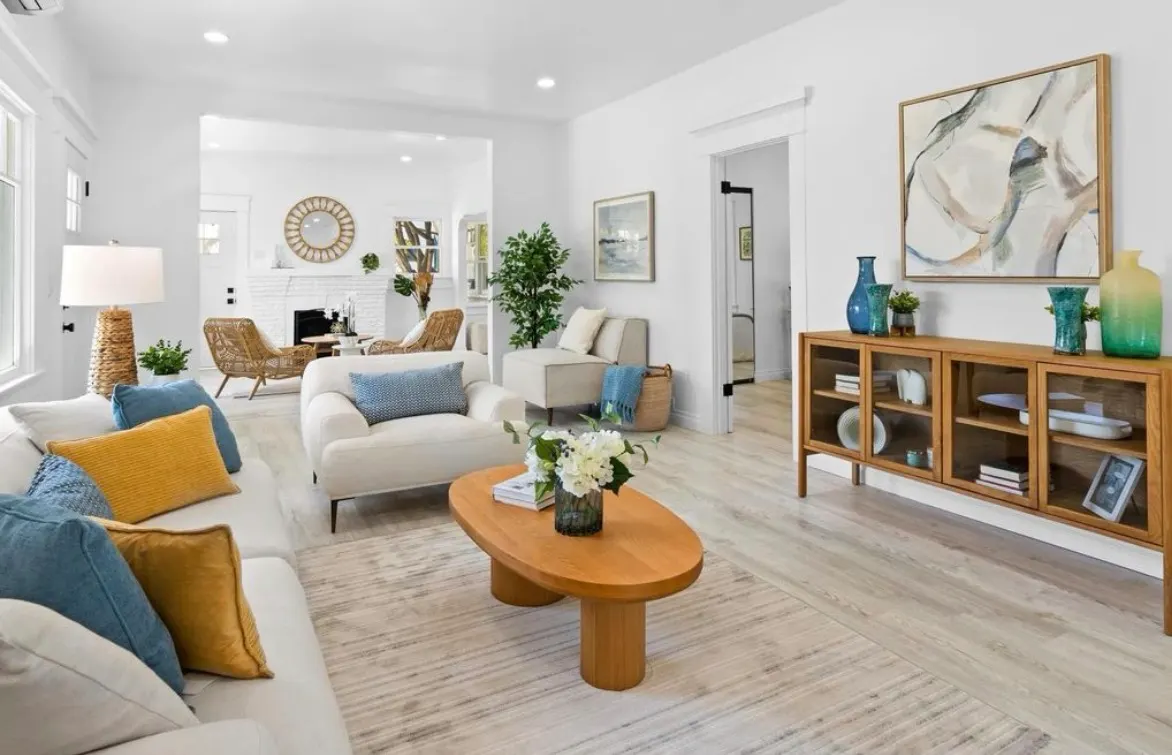 Bright, modern living room with light wood floors, white walls, and blue and yellow accents.