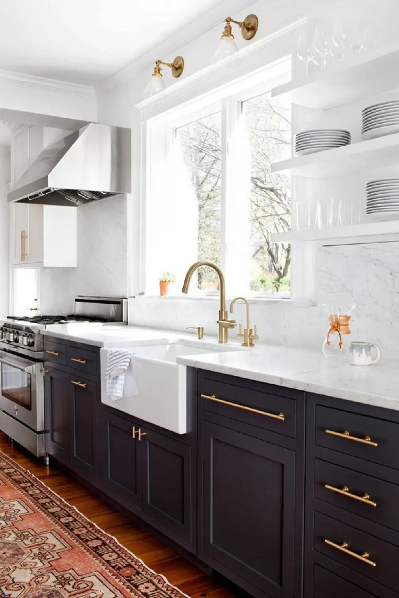 Classic kitchen with navy shaker cabinets, brass hardware, marble counters, and a farmhouse sink
