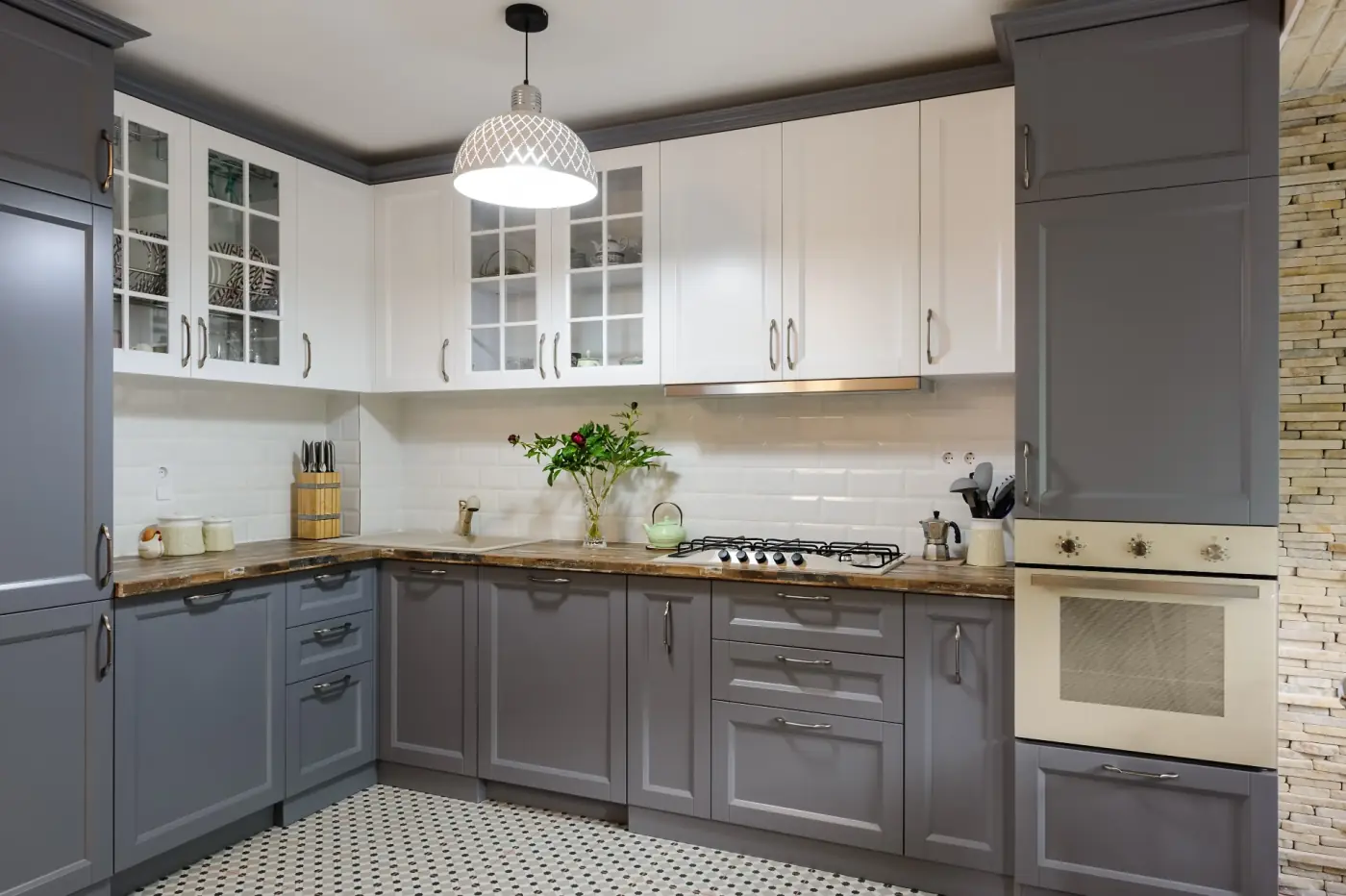 Two-tone shaker kitchen with white upper cabinets, gray base cabinets, butcher-block counter, and patterned tile floor