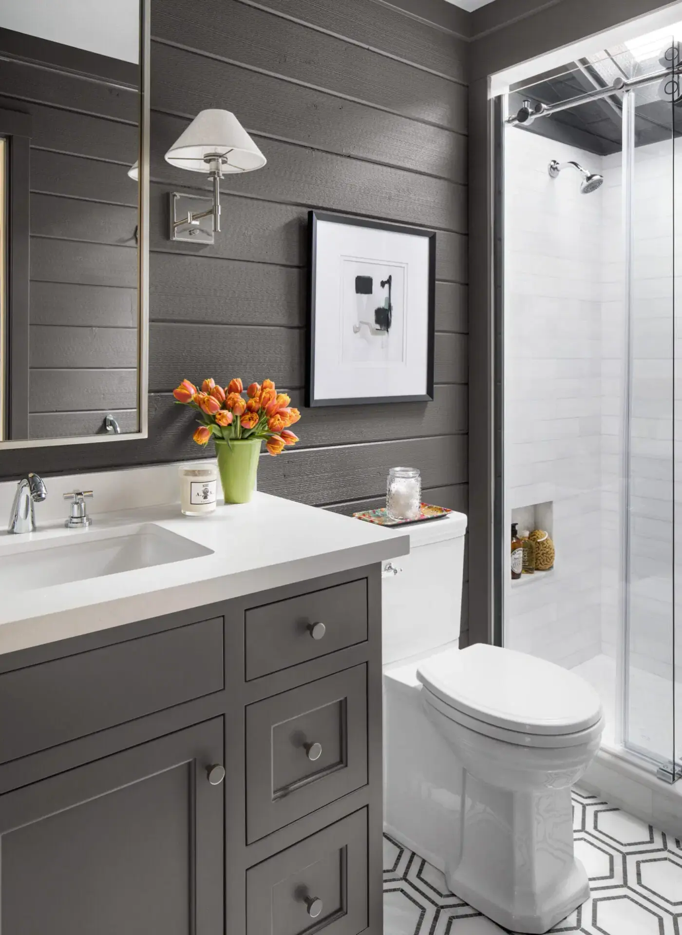 Charcoal shiplap bathroom with gray vanity, walk-in glass shower, white quartz counter, and hexagon tile floor
